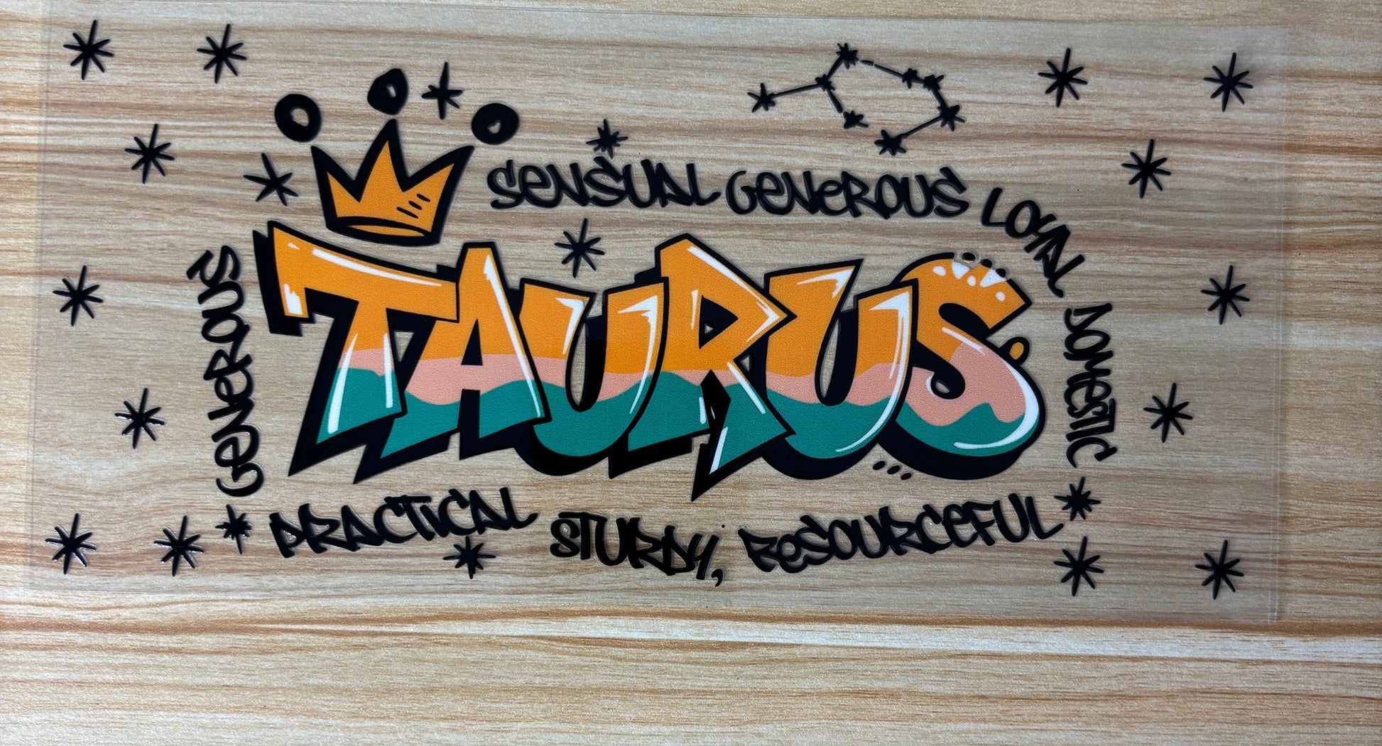 a colorful graffiti-style design with the word "Taurus" prominently displayed. Surrounding the word "Taurus" are various words and phrases such as "sensitive generous loving", "practical study", "resOURCEFUL", and "domicious". The overall design has a playful and artistic feel, with the use of stars and the word "Taurus" creating a visually striking composition.